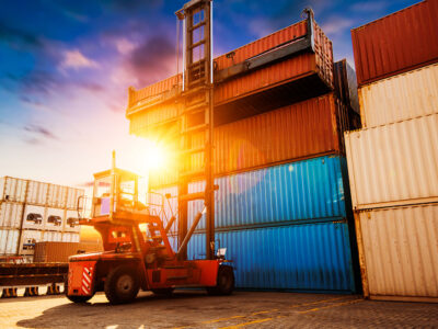 Forklift at port moving stacks of containers