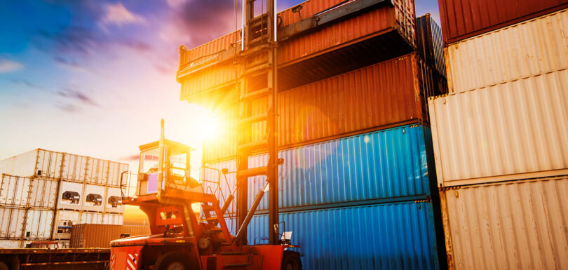 Forklift at port moving stacks of containers