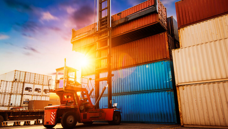 Forklift at port moving stacks of containers