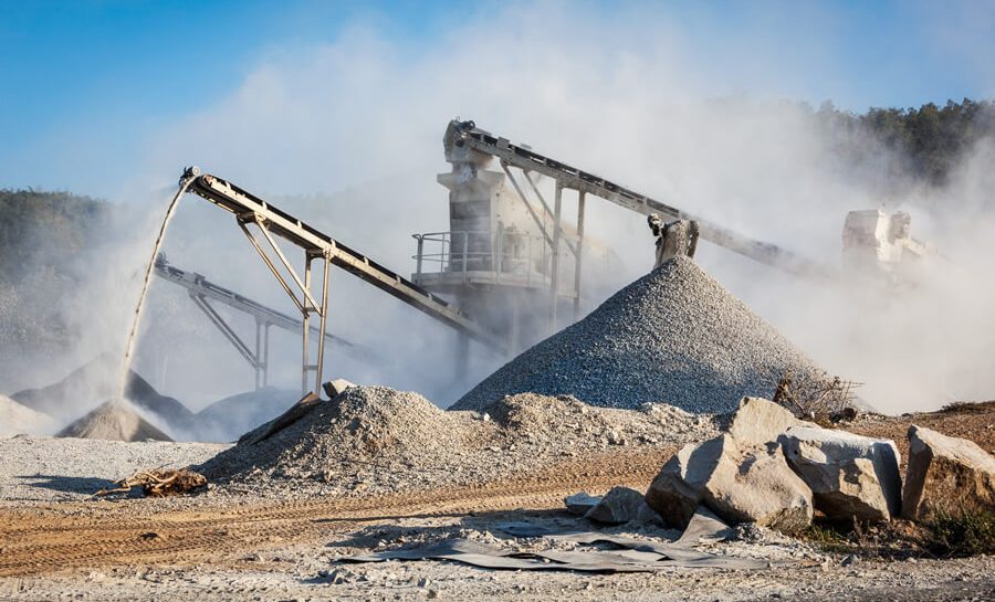 View of cranes, stone piles and sand piles at an industrial loading facility.